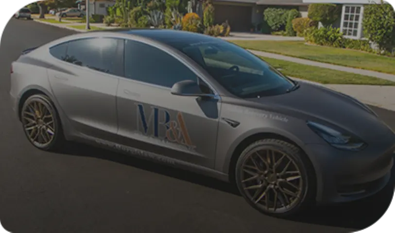 Gray MB&A-branded car parked on a residential street.